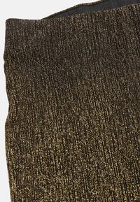 Sort og gylden tekstureret stof med et vævet mønster, der har metalliske tråde, som skaber en glitrende effekt. Glat, elastisk materiale.