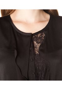 Blusa nera con una texture in satin, scollatura rotonda, dettagli in pizzo sul petto e chiusura a bottoni sulla parte frontale.