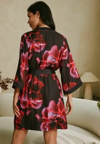 Musta kukallinen kimono, jossa on suuria punaisia ja vaaleanpunaisia orkideakuvioita, kolmANNELle neljännekselle hihat ja sidottava vyö. Sileä satiininen rakenne.