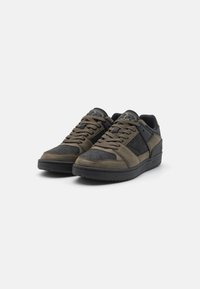 Sneaker neri e verdi oliva con tomaia in suede e pelle texture. Punta rotonda, lacci piatti, colletto imbottito e suola in gomma.