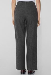 Pantalons gris à jambes larges en tissu doux avec une taille élastique. Présente une texture lisse et une coupe légèrement décontractée.