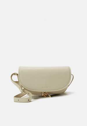Beige leren crossbodytas met verstelbare band, klepsluiting en kleine gouden bedeldetails die aan de voorkant hangen.