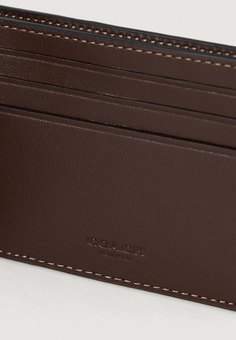 Porte-cartes en cuir marron avec plusieurs fentes et logo embossé "COACH NEW YORK", présentant des coutures détaillées le long des bords.