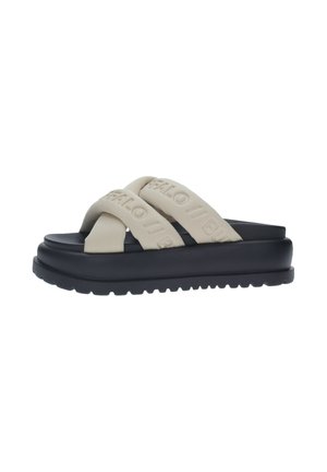 Sandalias deslizantes de goma beige con dos correas cruzadas y un logotipo en relieve. Suela negra gruesa con un fondo texturizado para mayor tracción.