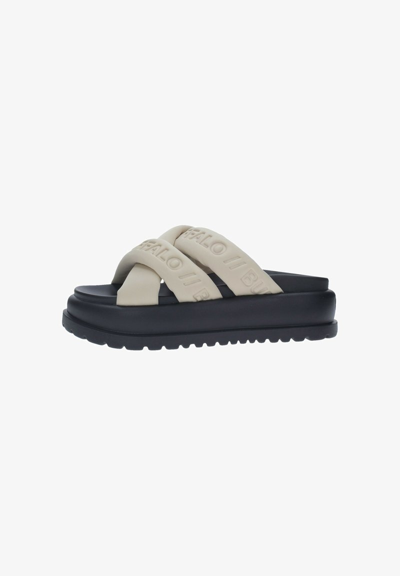 Sandalias deslizantes de goma beige con dos correas cruzadas y un logotipo en relieve. Suela negra gruesa con un fondo texturizado para mayor tracción.