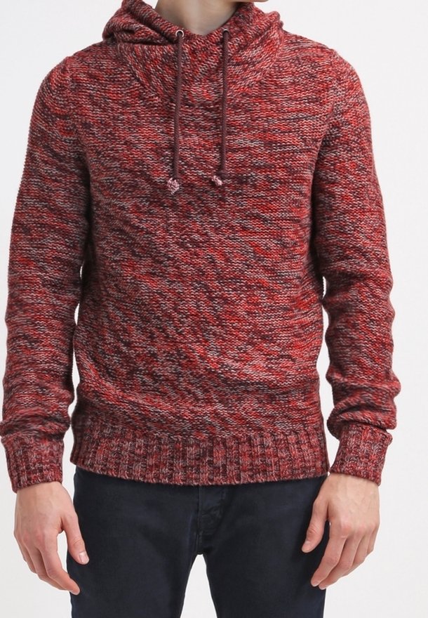Rote Strickkapuzenjacke mit strukturiertem Muster, Kordelzugverschluss und gerippten Bündchen. Kombiniert mit dunkler Jeans.