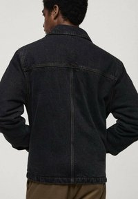 Schwarze Jeansjacke mit klassischem Design, ausgestattet mit einem Standardkragen, einer Rückenteilnaht und sichtbaren Nähten entlang der Kanten.
