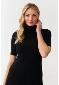 Must have käsivarte turtleneck kleit, mis on valmistatud ribakujulisest, venivast kangast, omades figuuri rõhutavat bodi ja voolavat seelikut.