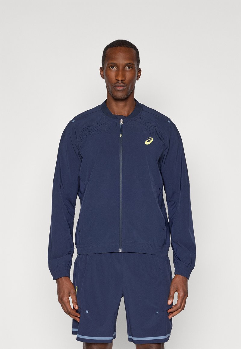 Ναυτικό αθλητικό μπουφάν με φερμουάρ μπροστά, χαλαρή εφαρμογή, ανα respirable ύφασμα και πλευρικές τσέπες. Διαθέτει λογότυπο στο στήθος και στον ώμο.