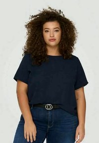 Marinblå kortärmad skjorta med lös passform, tillverkad av mjukt tyg. Matchad med jeans i denim och ett svart bälte med cirkulär hårdvara.