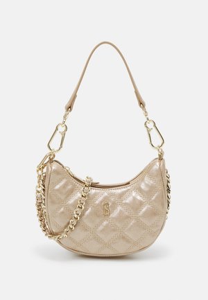 Sac à main matelassé beige avec une bandoulière en chaîne dorée et une petite poignée en cuir, avec une fermeture éclair dorée et un petit logo métallique à l'avant.