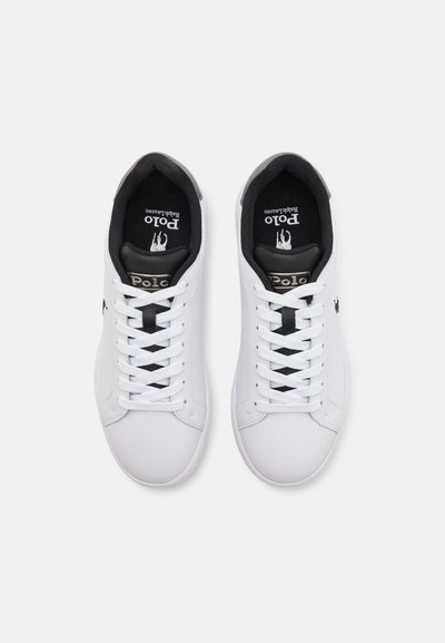 White lace-up sneakers with a smooth leather upper, black insoles, rubber soles, and a small embroidered logo on the side.