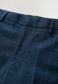 Dunkelblaue Karohosen aus strukturierter Stoff; mit einem flachen Taillenbund und einem subtilen Rautenmuster mit feinen blauen Linien.