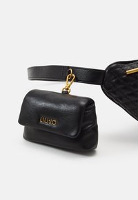 Mustankalvinen olkalaukku, jossa on tikattu pinta, kultaiset yksityiskohdat ja etutasku, jossa on "Liu Jo" -logo.