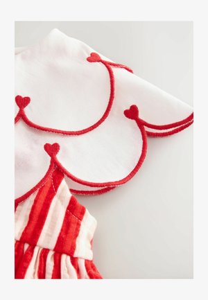 Rød og hvid kjole med en scalloped krave, der har rød hjertebroderi. Livet har skiftevis røde og hvide striber; blød tekstur.