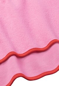 Coperta in pile rosa con bordo ondulato, rifinita in arancione. Texture morbida e finitura liscia. Progettata per calore e comfort.