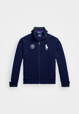 Jūras spēku zip-up jaka, izgatavota no auduma, ar baltām sānu svītrām, zaļu apkakli, izšūtu logotipu un ribotiem piedurkņu galiem un apakšmalu.