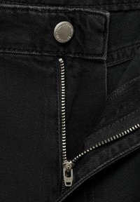 Sorte denimbukser med sølvknaplukning og YKK lynlås. Stof har en glat, let struktureret overflade.