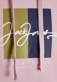 Lyserød hættetrøje med et multifarvet grafisk mønster, der har en mørkeblå og olivengrøn blok. Hvidt logotekst "Jack & Jones" og "ORIGINALS WORLDWIDE."