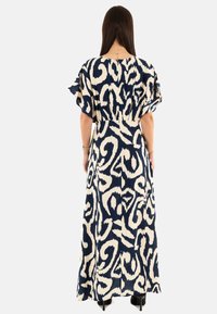 Abito maxi blu navy e crema con un motivo astratto a vortice, maniche corte a sbuffo e vita cinquetata, realizzato in tessuto leggero.