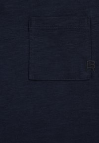 Tumši zila kokvilnas T-krekls ar krūšu kabatu ar izšūtu detaļu un izšūtu "R" logotipu atbilstošā krāsā. Gluda tekstūra.