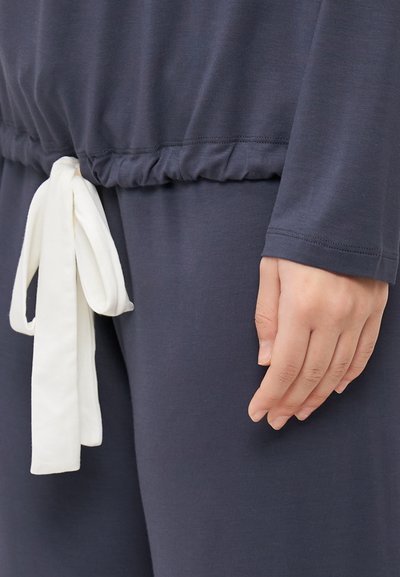 Navy loungewear top with a gathered waist and white tie detail, featuring long sleeves and soft, smooth fabric texture.