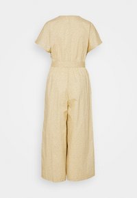 Gul blommönstrad jumpsuit med korta ärmar, midjebälte och vida ben, tillverkad av lättviktsmaterial.