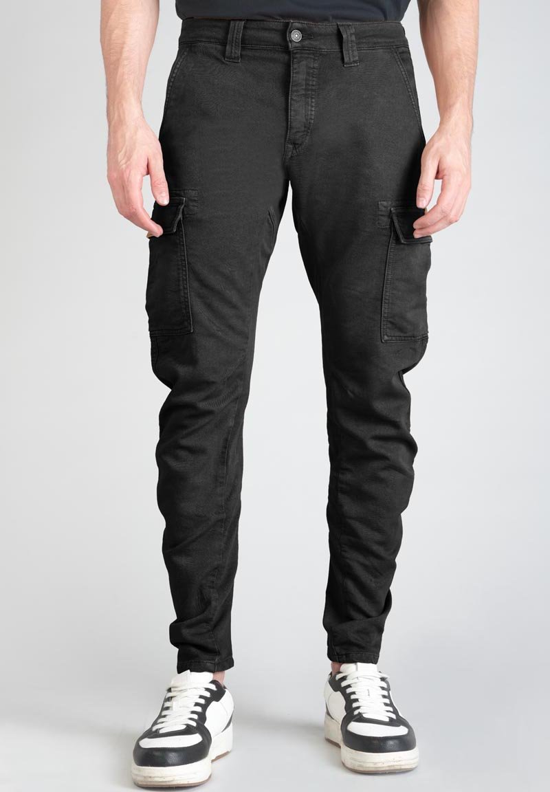 Pantalones cargo negros con un ajuste slim, que cuentan con bolsillos laterales y cierre de botón. La tela tiene una textura suave, combinada con zapatillas blancas.