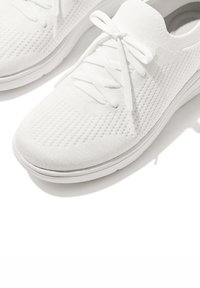 Witte sportieve sneakers gemaakt van ademend breimateriaal, met een gestructureerd patroon, platte veters en een gevoerde zool.