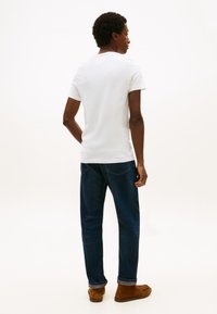 Valge puuvillane T-särk, lühikeste varrukatega, ümmarguse kaelusega. Kombineeritud tumeliste siniste teksadega, veidi lõdva istuvusega, ülesrullitud ääred. Pruunad seemisnahast kingad.