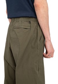 Heren olijfgroene broek van lichtgewicht stof. Voorzien van een elastische tailleband, zij- en achterzakken, en een gestructureerd oppervlak.