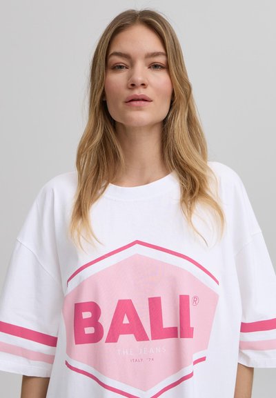 Camiseta blanca de gran tamaño con diseño gráfico en rosa que presenta la palabra "BALL" y dos franjas horizontales rosas en las mangas. Textura de algodón suave.