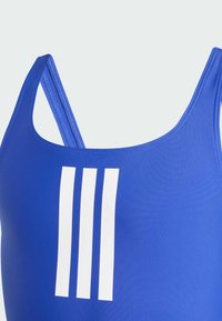 Plavi atletski kupaći kostim s teksturiranim završetkom, s tankim trakama i tri bijele okomite pruge sprijeda.