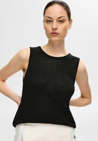 Svart ärmlös topp i stickad material, med rund halsringning och avslappnad passform, med en slät yta och minimala sömmar.