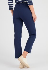 Pantaloni blu navy con vestibilità rilassata, cintura elastica e tasche laterali. Il materiale sembra liscio con un design strutturato.