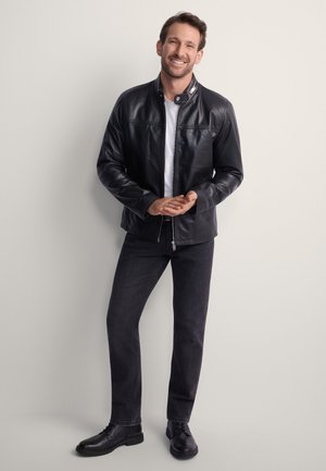 Czarna skórzana kurtka z kołnierzem, zamkiem błyskawicznym i przednimi kieszeniami, w połączeniu z ciemnymi dżinsami i czarnymi sznurowanymi butami.