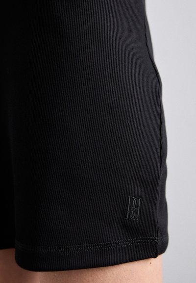 Schwarze gerippte Shorts mit einer glatten Textur, versehen mit einem dezenten gestickten Logo am Saum und einer figurnahen Passform.