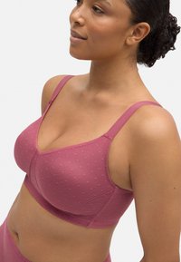 Sujeción de color malva con textura de puntos, tirantes ajustables y suave acolchado. Confeccionada con material elástico para mayor comodidad y soporte.