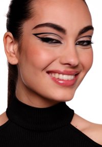 Ritratto ravvicinato di una persona che indossa un dolcevita nero a coste. Presenta un intenso eyeliner a punta alata, labbra carnose e pelle liscia con una leggera lucentezza.