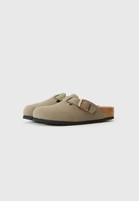 Zoccoli in suede verde con una forma arrotondata, cinturino in pelle regolabile e soletta in sughero. Suola in gomma per una buona presa e durata.