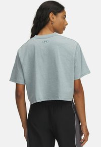 Lichtblauw cropped t-shirt van zachte stof met een ronde hals, korte mouwen en een merklogo op de achterkant van de hals. Gepaard met zwarte broek.