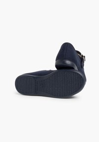 Zapatos de ante azul marino con punta redonda, correa con hebilla dorada y suela de goma texturizada. Hechos en España.