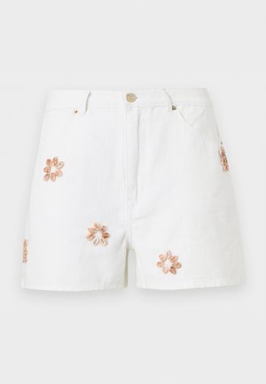 Shorts en denim blanc avec poches avant et fleurs coquillage décoratives beiges brodées à l'avant et sur le côté.