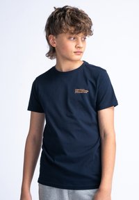 Navyblauwe T-shirt met korte mouwen van katoen, met een kleine gedrukte tekstdetail op de bovenste linker borst. Eenvoudig ontwerp met ronde hals.