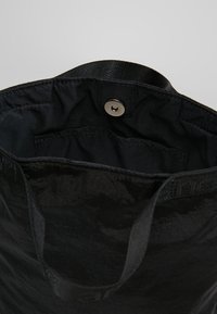 Borsa a tracolla nera con fodera in tessuto, tasca interna e chiusura a bottone metallico, che mostra l'apertura superiore e le maniglie.