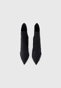 Svarte ankelstøvler med spiss tå, laget av glatt materiale. Har en minimal design og elastiske sideder. Ingen synlig maskinvare.