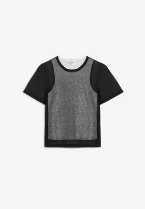 Schwarzes kurzärmeliges Oberteil mit transparentem Vorderteil, das kleine Polka-Dots zeigt, und einem runden Ausschnitt.