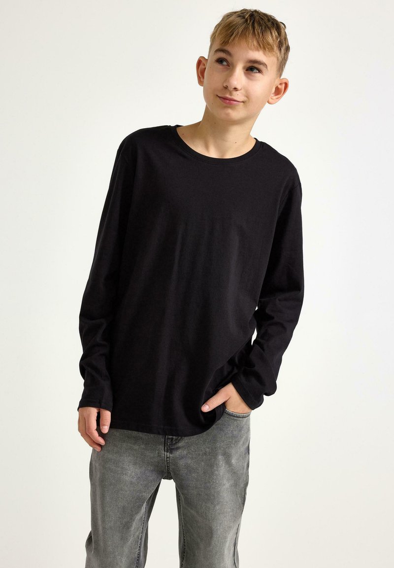 Sort langærmet T-shirt lavet af blødt stof, med rund halsudskæring og afslappet pasform, parret med lysegrå denimbukser.