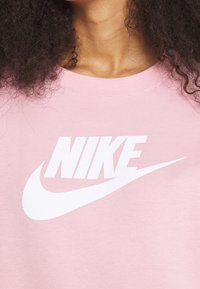 Rosa sweatshirt med crew neck, med en stor vit "NIKE"-logotyp och swoosh-design på framsidan, tillverkad av mjukt bomullsmaterial.