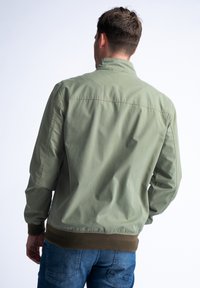 Olivově zelená bombarďáková bunda se zipovým zapínáním, žebrovanými manžetami a lemem. Hladká tkanina s lehkým pocitem, s jednoduchým designem.